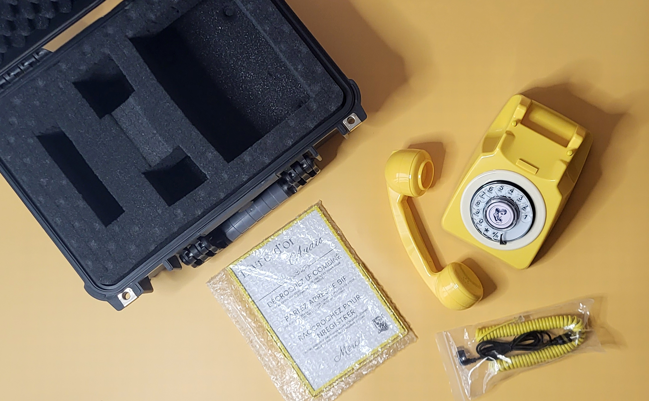 Valise ouverte : mousse sur mesure, téléphone vintage, combiné et cadre explicatif