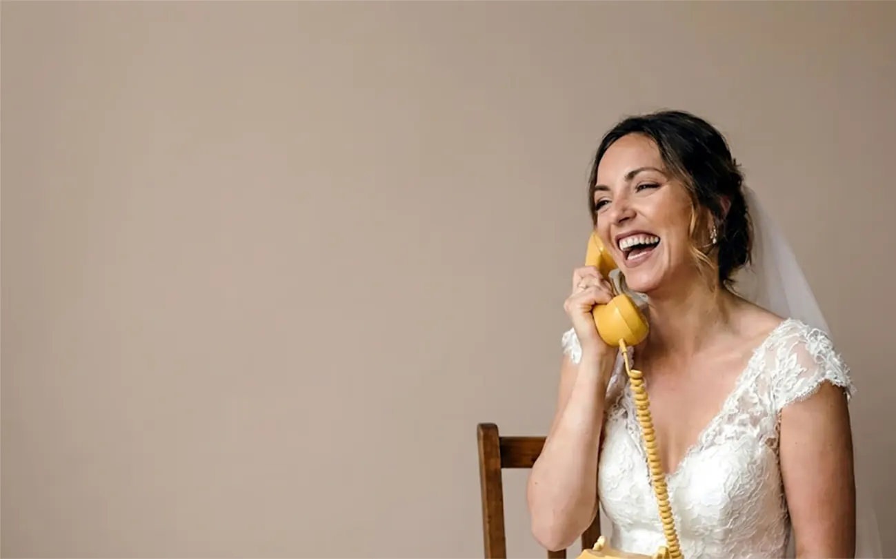 Sposa sorridente con la cornetta di un telefono vintage giallo all’orecchio
