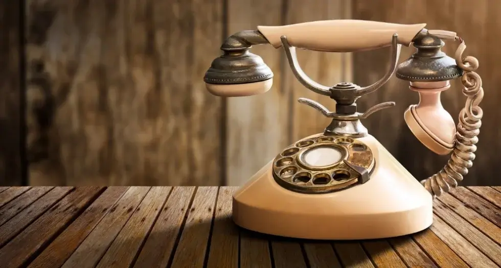 Téléphone rétro en bois sur une table, illustrant le concept du Livre d'Or Audio